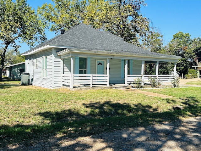 view of front of property featuring a front lawn, central air condition unit, and covered porch