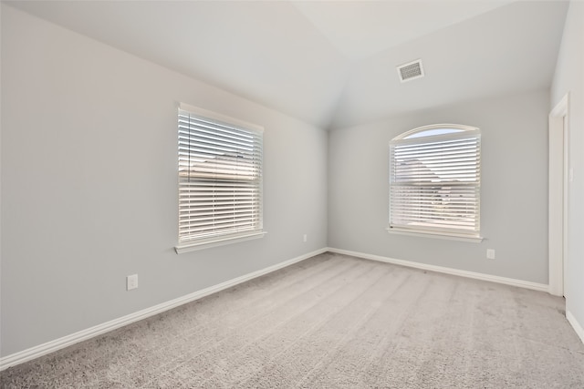 spare room with light colored carpet and lofted ceiling