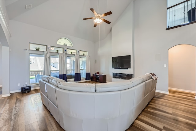 living room with ceiling fan, light wood-type flooring, and high vaulted ceiling