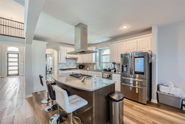 kitchen with stainless steel appliances, light hardwood / wood-style flooring, island range hood, and white cabinetry