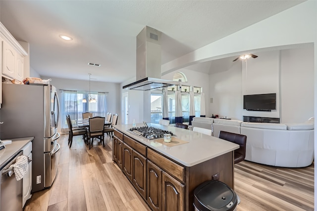 kitchen featuring light wood-type flooring, dark brown cabinetry, a center island, hanging light fixtures, and appliances with stainless steel finishes