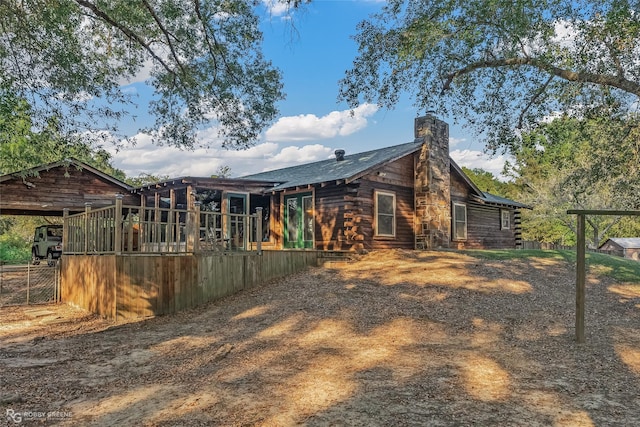 rear view of house featuring a chimney and log siding