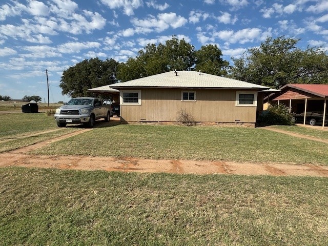 view of side of home featuring a carport and a lawn