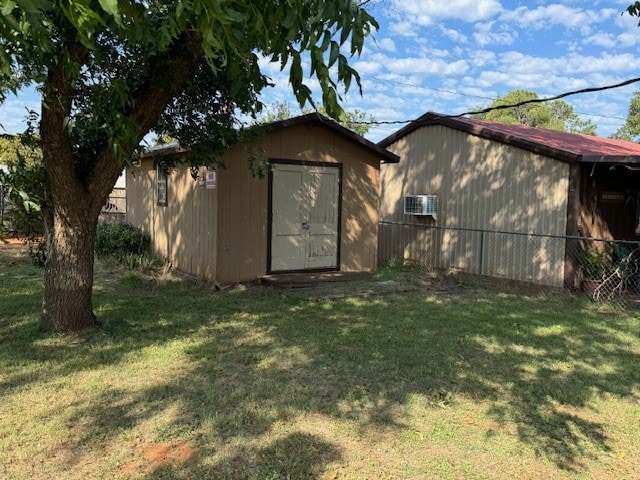 back of house with a storage unit and a lawn