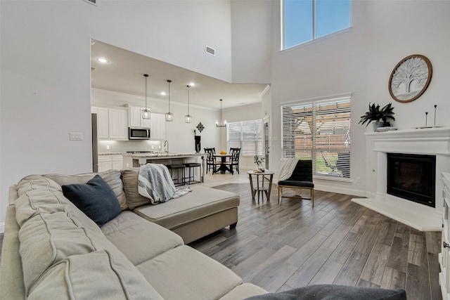 living room with a wealth of natural light, hardwood / wood-style floors, crown molding, and a high ceiling