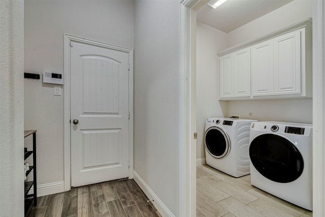 laundry area featuring washing machine and dryer, light hardwood / wood-style flooring, and cabinets