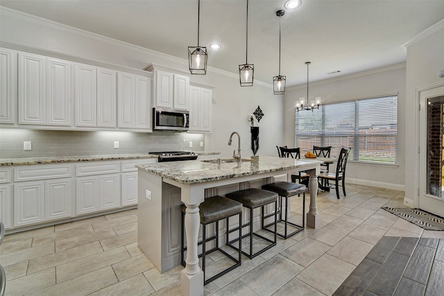 kitchen with white cabinets, sink, stainless steel appliances, and an island with sink