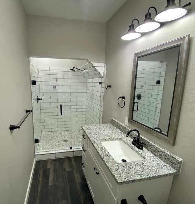 full bath with vanity, baseboards, a stall shower, and wood finished floors