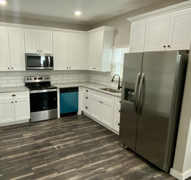 kitchen with dark hardwood / wood-style flooring, sink, stainless steel appliances, backsplash, and white cabinetry