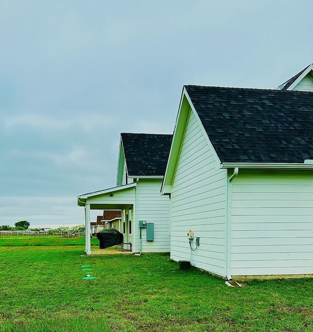 view of home's exterior with a shingled roof and a lawn
