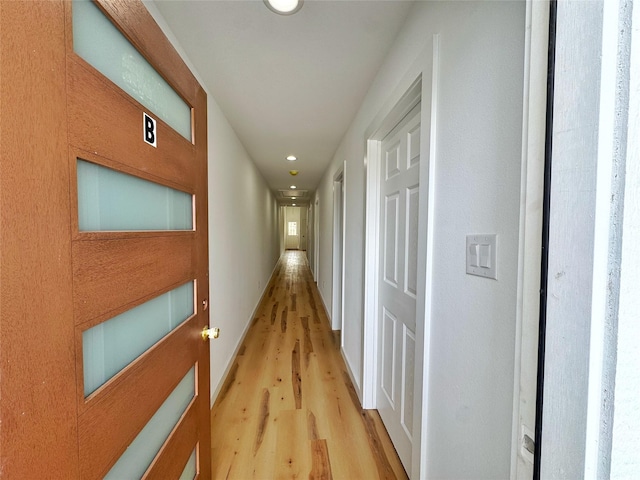hallway featuring baseboards, light wood-style flooring, and recessed lighting