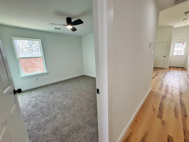 empty room featuring baseboards, carpet flooring, visible vents, and a ceiling fan