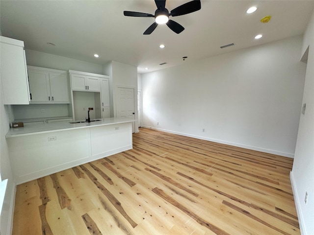 kitchen featuring light countertops, a sink, a peninsula, visible vents, and ceiling fan