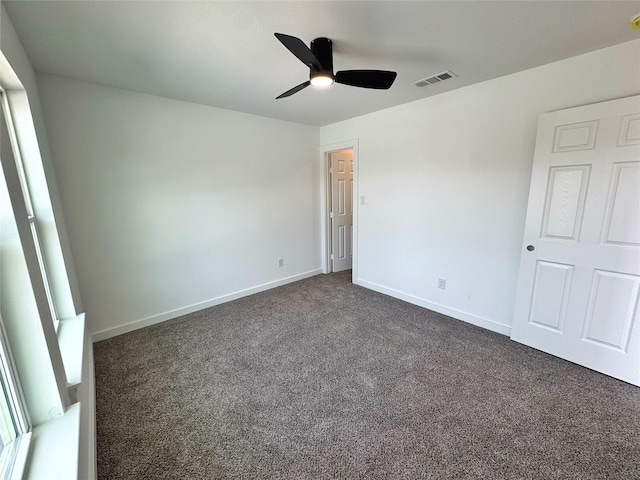 unfurnished room featuring ceiling fan, baseboards, visible vents, and dark carpet