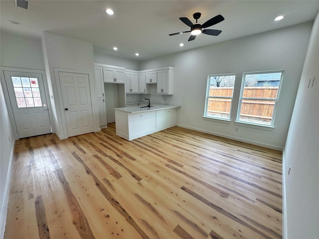 kitchen featuring recessed lighting, a sink, a peninsula, and light wood finished floors