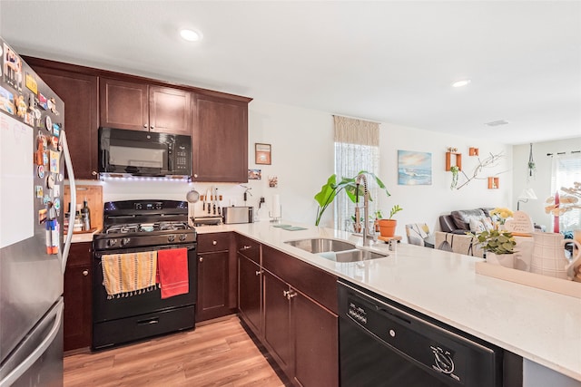 kitchen with black appliances, sink, kitchen peninsula, light hardwood / wood-style flooring, and dark brown cabinets