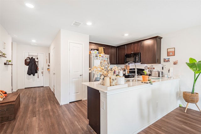 kitchen with dark brown cabinetry, stainless steel fridge, dark hardwood / wood-style flooring, and kitchen peninsula