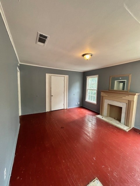 unfurnished living room with visible vents, a fireplace, wood finished floors, baseboards, and ornamental molding