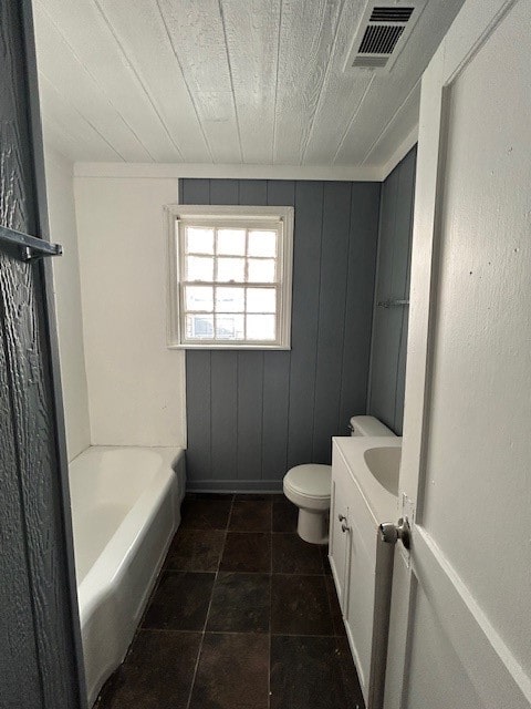 bathroom with wood walls, toilet, tile patterned floors, a bathing tub, and vanity