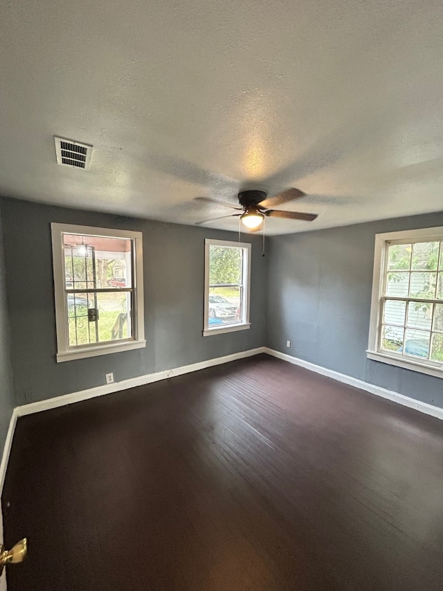 empty room with baseboards, a ceiling fan, dark wood-style flooring, and visible vents