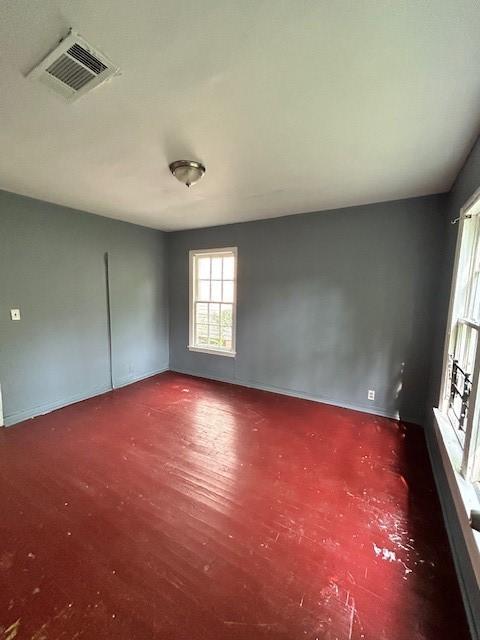 empty room featuring baseboards, wood finished floors, and visible vents