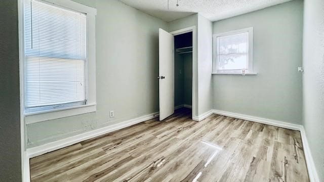 unfurnished bedroom with a closet, a textured ceiling, and light hardwood / wood-style flooring