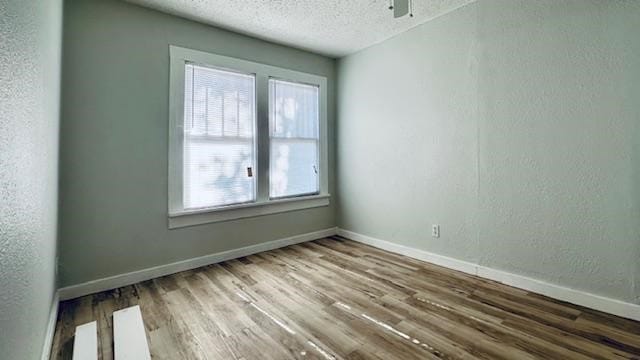 empty room with a textured ceiling, hardwood / wood-style flooring, and ceiling fan