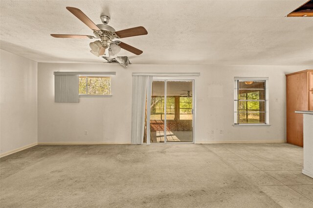 carpeted empty room featuring ceiling fan and a textured ceiling