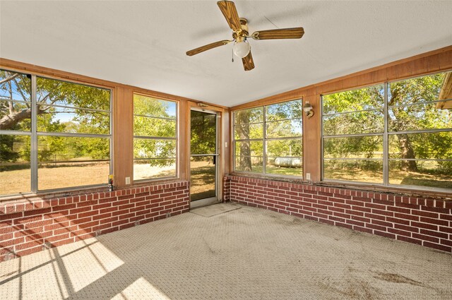 unfurnished sunroom featuring vaulted ceiling, a wealth of natural light, and ceiling fan