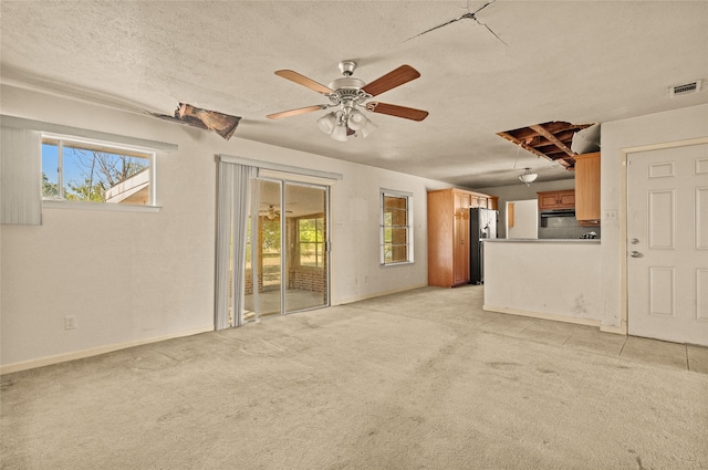 unfurnished living room featuring ceiling fan, light colored carpet, and a textured ceiling