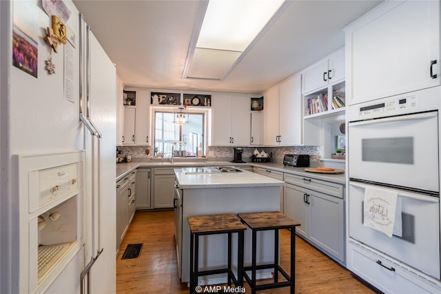 kitchen with a breakfast bar area, white cabinets, a kitchen island, and white appliances