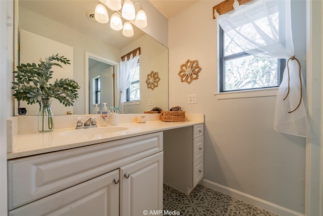 bathroom featuring tile patterned floors, vanity, a healthy amount of sunlight, and an inviting chandelier