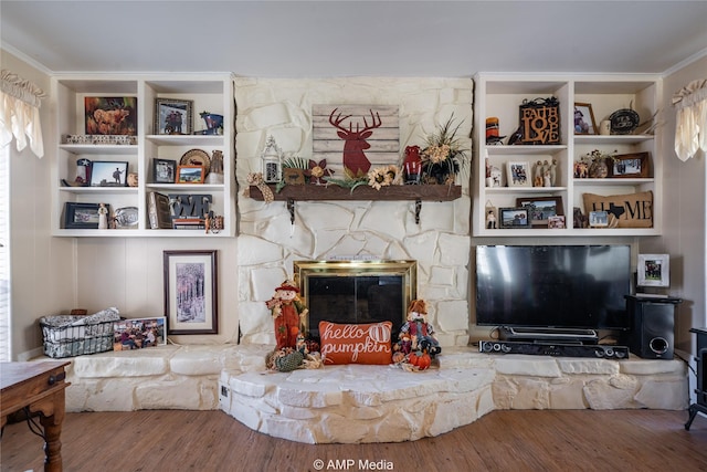 living room featuring hardwood / wood-style floors, a stone fireplace, and crown molding