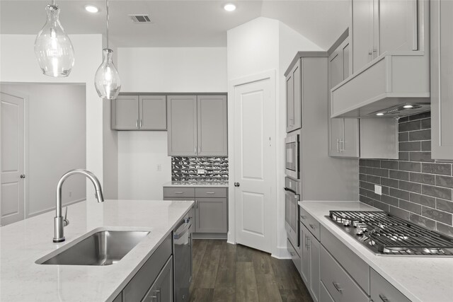 kitchen featuring light stone countertops, dark hardwood / wood-style floors, stainless steel appliances, sink, and hanging light fixtures