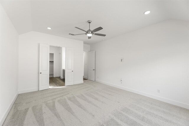 unfurnished bedroom featuring light colored carpet, vaulted ceiling, and ceiling fan