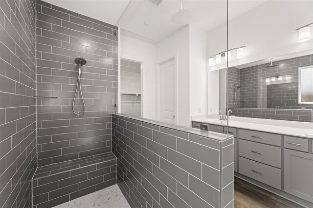 bathroom featuring vanity, hardwood / wood-style floors, and tiled shower