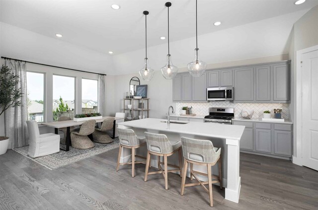 kitchen featuring decorative light fixtures, gray cabinets, stainless steel appliances, and sink