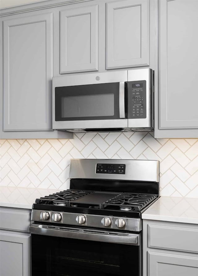 kitchen with appliances with stainless steel finishes, tasteful backsplash, and gray cabinetry