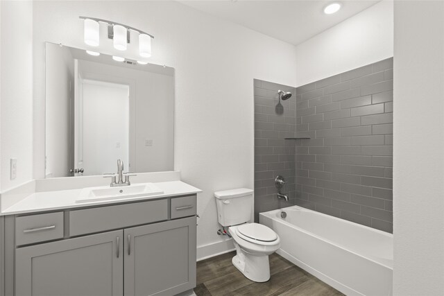 full bathroom with vanity, tiled shower / bath combo, toilet, and hardwood / wood-style flooring