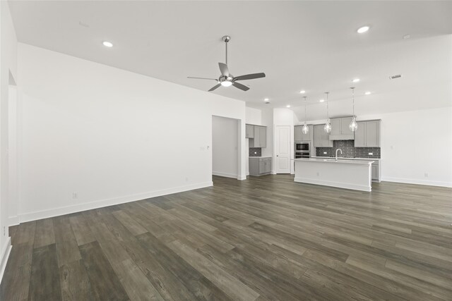 unfurnished living room with dark wood-type flooring, sink, and ceiling fan