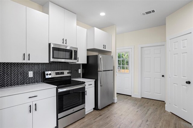 727 W Parnell St, Denison, TX 75020 - kitchen with stainless steel appliances, tasteful backsplash, light countertops, light wood finished floors, and white cabinetry