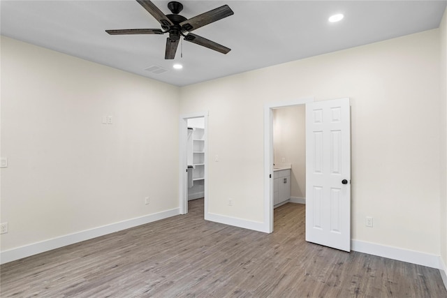 unfurnished bedroom with ceiling fan, light hardwood / wood-style flooring, a closet, a spacious closet, and ensuite bathroom