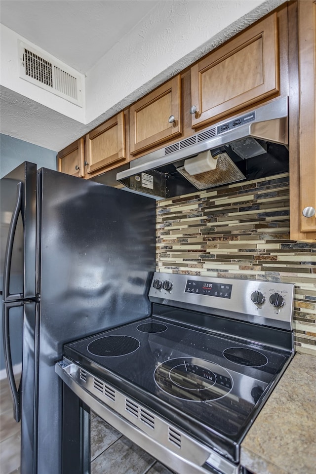 kitchen with tile patterned floors, decorative backsplash, and stainless steel range with electric cooktop