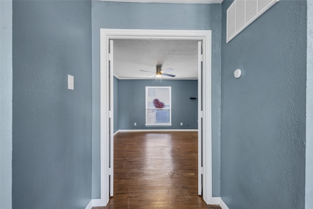 corridor featuring hardwood / wood-style flooring, crown molding, and a textured ceiling