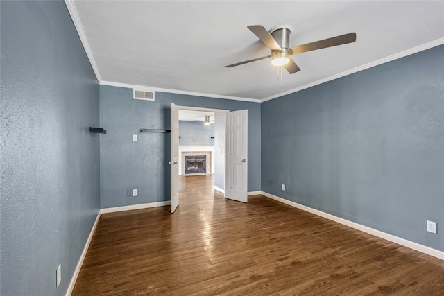 unfurnished bedroom featuring a fireplace, ceiling fan, dark hardwood / wood-style flooring, and crown molding