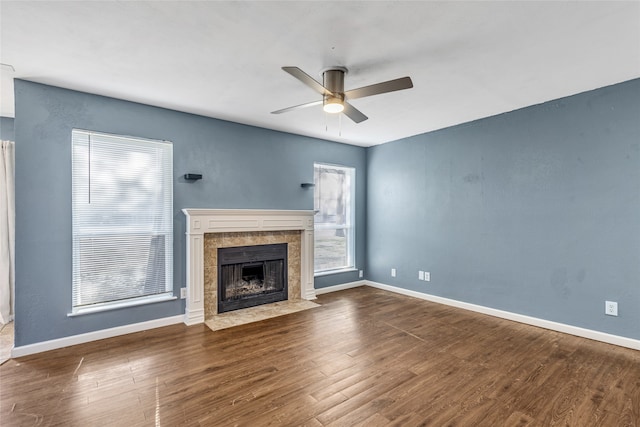 unfurnished living room with ceiling fan, dark wood-type flooring, and a tiled fireplace