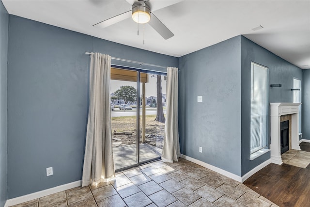 empty room featuring ceiling fan and a tile fireplace