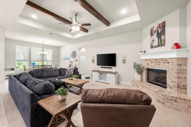 living room featuring beam ceiling, a fireplace, light hardwood / wood-style floors, and a raised ceiling