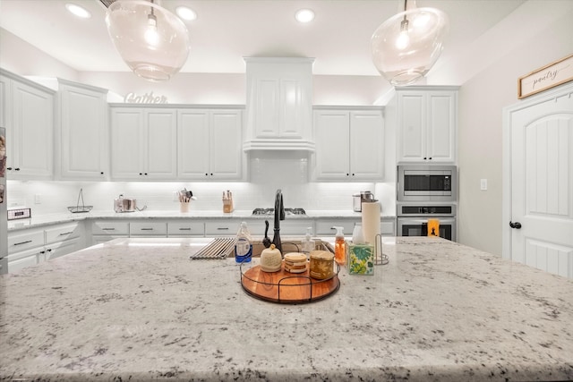 kitchen featuring light stone countertops, backsplash, hanging light fixtures, stainless steel appliances, and white cabinets