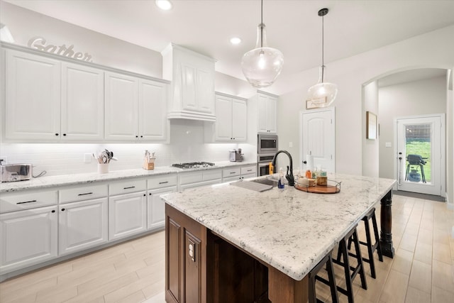 kitchen featuring appliances with stainless steel finishes, a center island with sink, and white cabinets